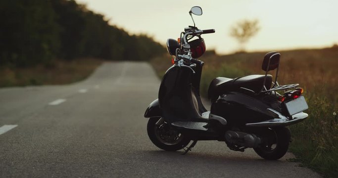 The motorbike is standing on the road with a nice sunset view