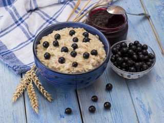 oat porridge with black currant on a blue wooden table. 