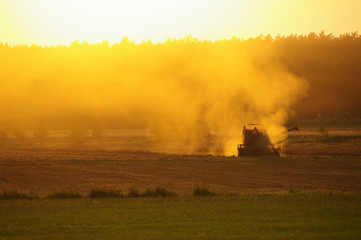 Fototapeta na wymiar Harvester against hot orange sunset background