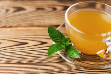Full glass cup of green tea and mint on old wooden table. Healthy concept