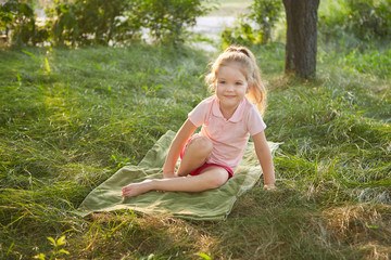 Naklejka na ściany i meble Little girl is sitting on the grass