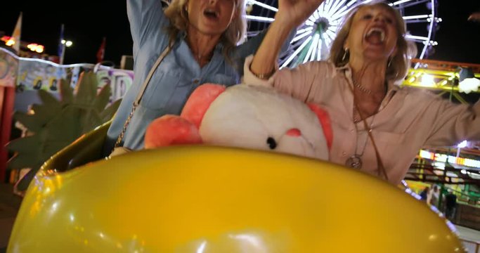 Excited senior women having fun on fairground roller coaster ride