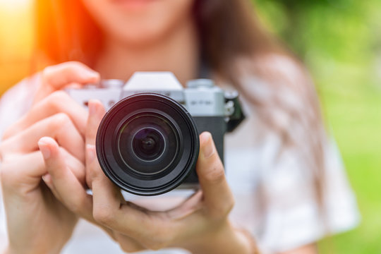 closeup front lens of mirrorless camera in woman teen photographer