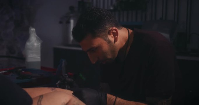 Tattoo artist working on client's tattoo in professional tattoo studio