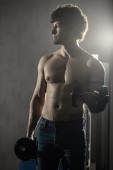 Muscular man trains biceps dumbbells in the gym, hand training