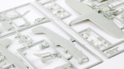 kit for assembling gray plastic airplane model on white bsckground