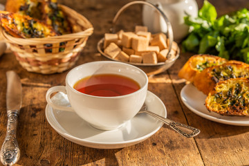 Lunch - tea and traditional French baguette toast with butter, parsley, garlic and basil on an old rustic wooden table