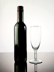 Wine bottle and glass of wine on table with white background.