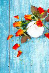cosmetic creams and rose flowers on blue wooden table background