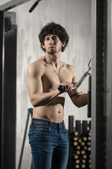 Fototapeta na wymiar Muscular person trains in gym, performs exercise on hands, bare torso, muscles are strained