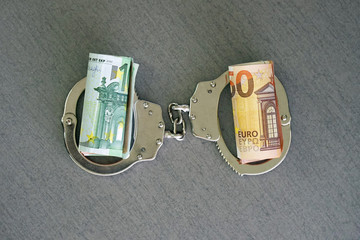 roll Euro money bills (banknotes) of 100 and 50 in handcuffs. Euro bills with handcuffs. Handcuffs...
