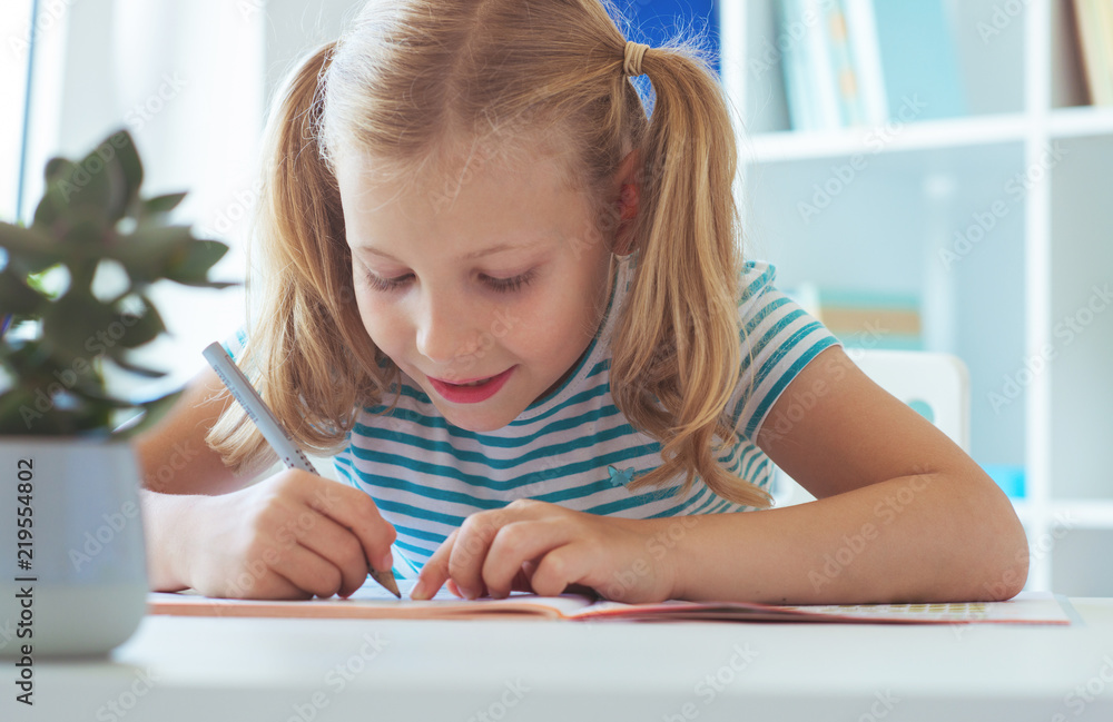 Wall mural portrait of schoolgirl at classroom writing at the table