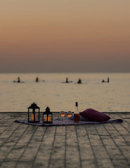 Summer sea sunset. Romantic picnic on the beach. Bottle of wine, glasses, candles, plaid and...