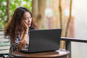 Young freelance woman using laptop to work outside coffee shop. Business person using laptop to communicate. Female student using laptop and study outside cafe in free time.