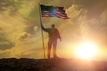 Silhouette of man holding US flag American on the mountain. The concept of Independence Day. a successful silhouette winner, a man waving an American flag on top of a mountain peak