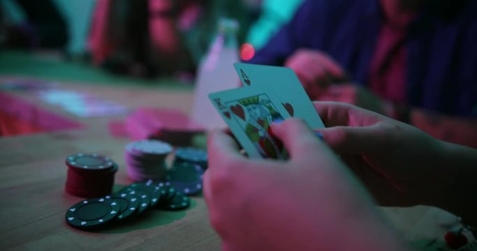 Close-up of woman holding cards while playing blackjack with friends