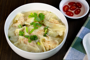 Shrimp wonton in hot soup in white bowl on wooden table Asia food