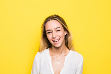Obraz premium Young blonde woman dressed casually making faces at camera, blinking isolated on yellow background