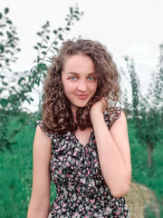 Naklejka premium young girl with dark curly hair smiling at camera on nature