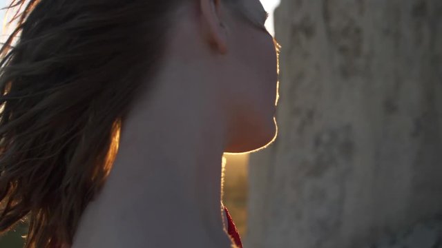 Close Up Portrait Of Young Woman With Red Hair Blowing In Wind Looking At Sunset Wearing Red Dress