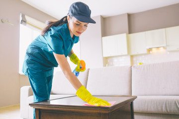 Professional cleaner wahsing surface of table. she uses rag and spray. Girl does it careful.