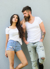 Young and stylish. Couple white shirts cuddle near grey wall. Hipster bearded brutal and stylish fashionable girl hang out. Couple friends hang out together. Youth stylish outfit simple but modern