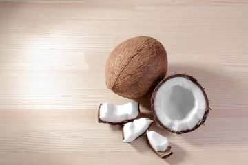 Fototapeta na wymiar a large fresh coconut and pieces of coconut on a natural wooden background. top view
