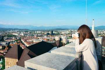 Fototapeta na wymiar Girl with camera taking photos of cityscape in Ljubljana Slovenia