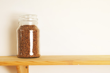 Buckwheat in a glass jar, isolated on a wooden board background and white background. Copy space.