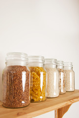 Various uncooked cereals, grains, pasta, bukwheat, rice, oat meals. Healthy cooking in glass jars on wooden table. Balanced dieting food.