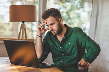 Young man having sressful time working on laptop