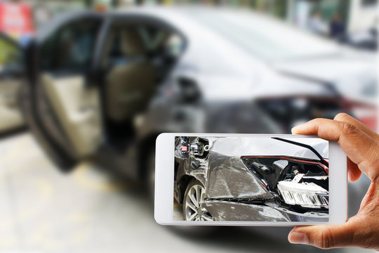 Close up hand holding smartphone and view photo of car accident