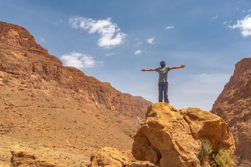 A man opening her arms, connected with the surroundings of the spectacular scenery in Morocco.