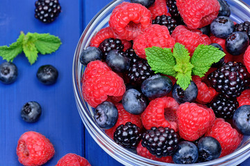 Fresh berries in a transparent bowl on table