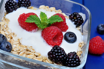 Granola with berries and yoghurt in a transparent bowl on wooden table