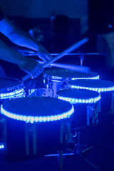 Drummer playing his drum kit on concert in club. Warning - Focus on the drum, authentic shooting with high iso in challenging lighting conditions. vertical photo