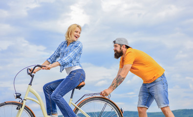 Support helps believe in yourself. Support and friendship. Woman rides bicycle sky background. Service and assistance. Man helps keep balance ride bike. Girl cycling while man support her