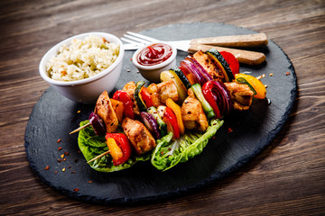 Kebabs - grilled meat with french fries and vegetables on wooden background 