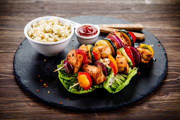 Kebabs - grilled meat with french fries and vegetables on wooden background 