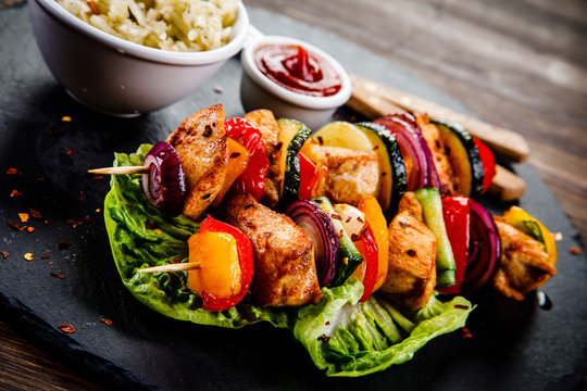 Kebabs - grilled meat with french fries and vegetables on wooden background 