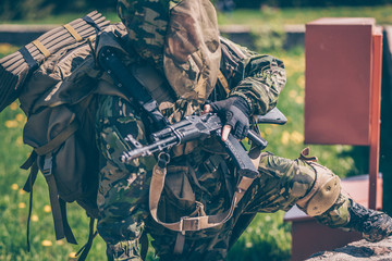 The military man in full army equipment overcomes the stone wall
