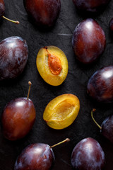 Fresh plums on a black background, top view