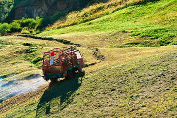 Fototapeta premium Worker cutting hay on meadow CH