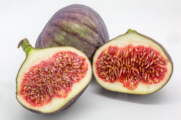 Fresh figs against a white background, with one cut to show the seeds