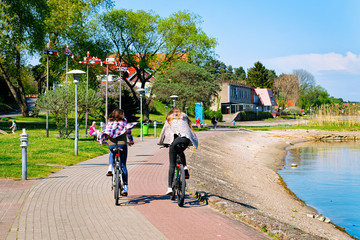 Girls riding bicycle Nida resort at Curonian Spit Baltic Sea