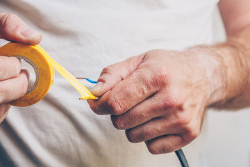 Electrician performs electrical work - isolates electric copper cable with insulation tape