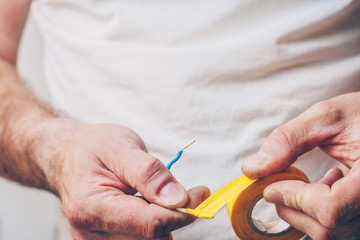 Electrician performs electrical work - isolates electric copper cable with insulation tape