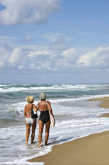 Two elderly women walking and talking on the beach. Sabaudia, Lazio, Italy