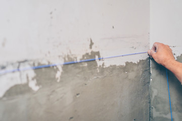 finishing work - the worker makes a marking for the tiles on the wall
