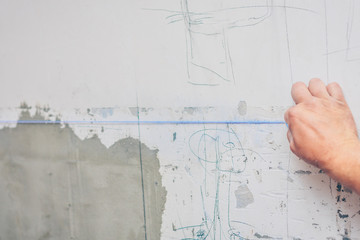 finishing works - the worker makes a marking with chalk with the help of a padded cord on the wall